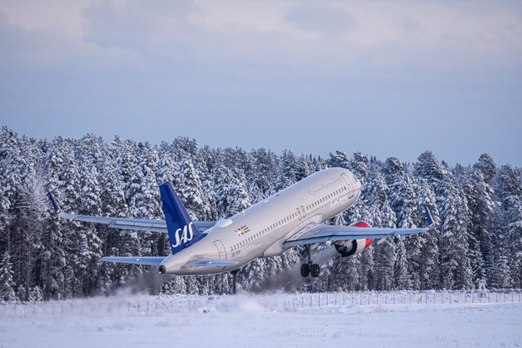 a Scandinavian airlines airplane takking off on a winter day snow